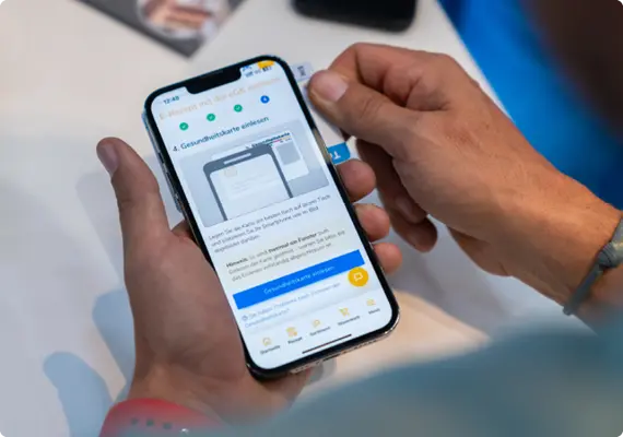 Eine Person hält eine Gesundheitskarte an ihr Smartphone, um sie mithilfe der CardLink-Funktion der WAVE App einzulesen.